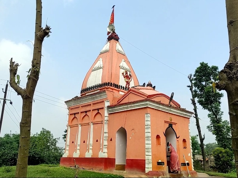 The orange temple exterior at Kandaha, with a worshipper near the entrance